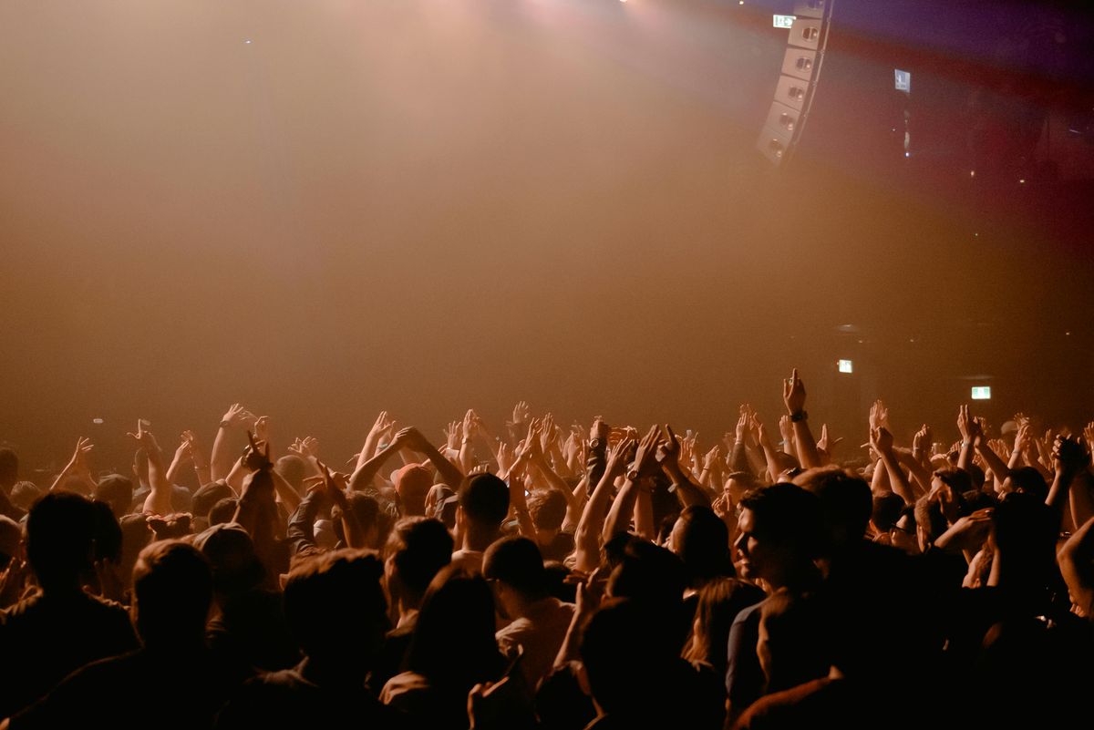 Een groep mensen die hun handen omhoog houden bij een concert. Voordat het gaat beginnen